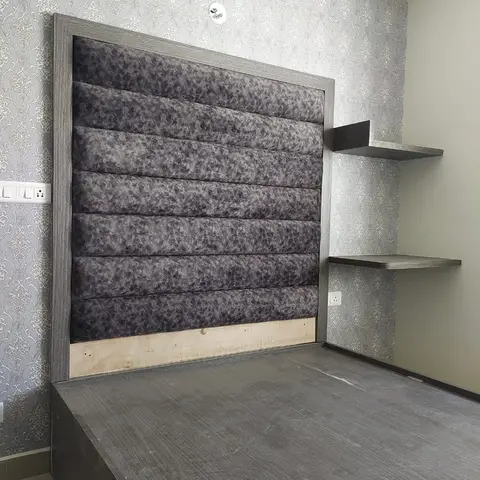 Master bedroom with a channel-tufted grey upholstered headboard on a wood-look platform bed against a grey damask wallpaper wall