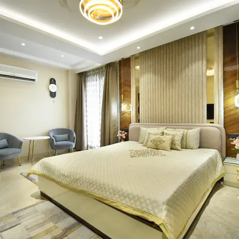 Master bedroom with a channel-tufted fabric headboard wall flanked by dark wood chevron panelling, twin drop pendant lights, matching bedside tables