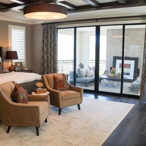 Master bedroom with a coffered dark wood ceiling, tufted leather headboard, a pair of accent armchairs on a geometric rug