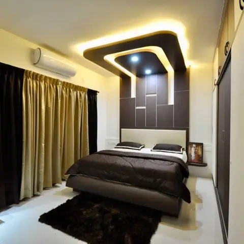 Master bedroom with a dark walnut panelled headboard wall lit by a stepped cove ceiling, gold curtains, and a dressing mirror corner.