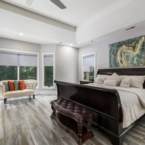 Master bedroom with a dark wood sleigh bed dressed in 'Mr' and 'Mrs' pillows, a tufted leather bench at the foot