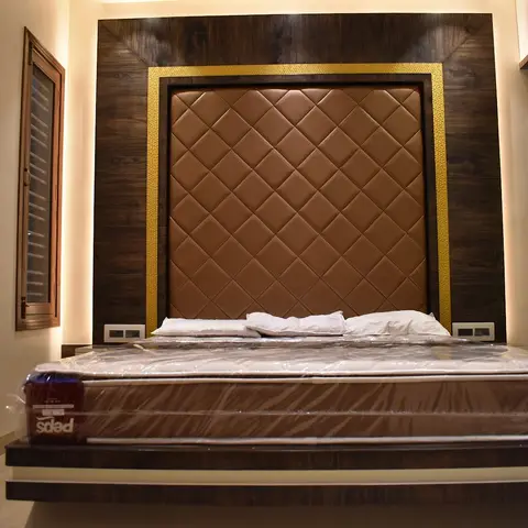 Master bedroom with a diamond-quilted tan leather headboard framed in gold trim against a dark wood panelled wall, and a floating wood bed base