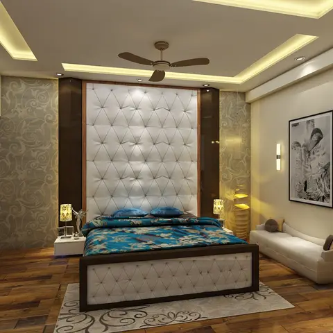 Master bedroom with a diamond-tufted upholstered headboard wall, teal floral bedding, damask wallpaper, and a warm cove-lit stepped false ceiling.