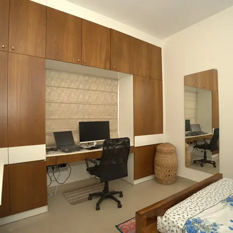 Master bedroom with a floor-to-ceiling walnut-veneer wardrobe wall that wraps around an integrated study desk with a roman blind