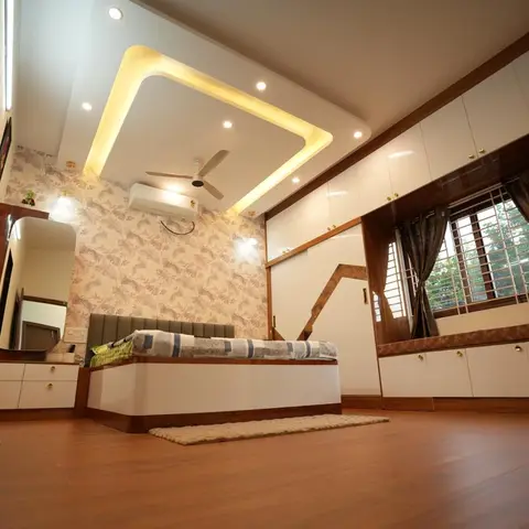 Master bedroom with a floral wallpaper accent wall, a backlit square cove ceiling, a wood dressing unit with mirror, and a window-seat storage bench.