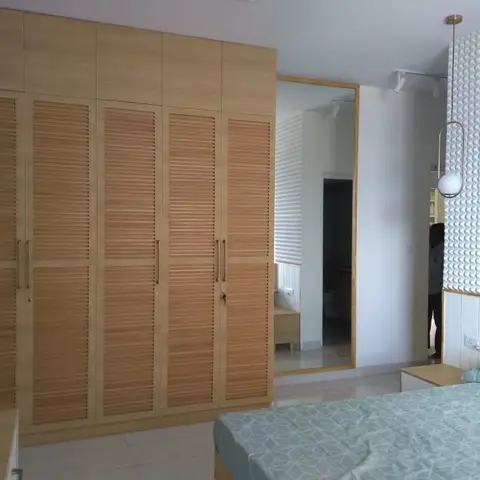 Master bedroom with a full-height louvred wood wardrobe, a 3D geometric textured accent wall behind the headboard
