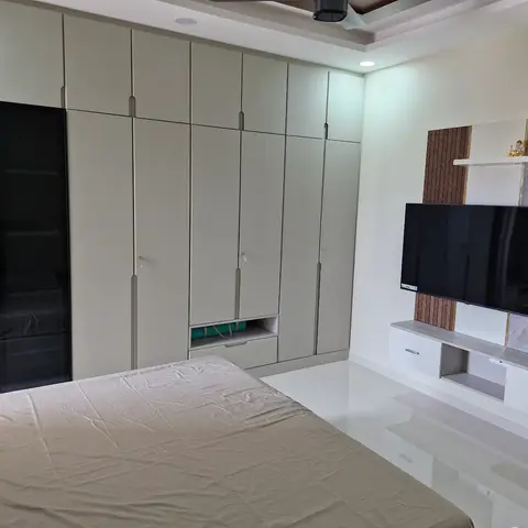 Master bedroom with a full-height light-grey wardrobe wall including a mirrored shutter