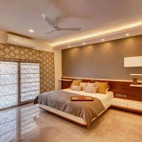 Master bedroom with a full-width wood headboard wall with a floating nightstand and open display shelf, a cove-lit ceiling