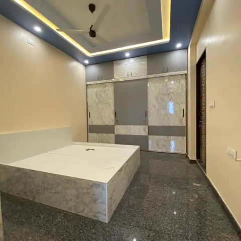 Master bedroom with a marble-laminate platform bed and matching sliding wardrobe, under a cove-lit false ceiling with a navy border.