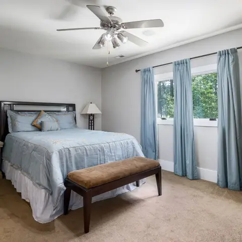 Master bedroom with a queen bed in powder-blue bedding flanked by matching nightstands and lamps, blue floor-length curtains