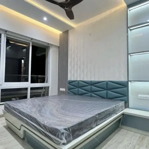 Master bedroom with a teal geometric-tufted headboard, a 3D wave-textured accent wall, a backlit frosted-glass wardrobe, and a cove-lit ceiling