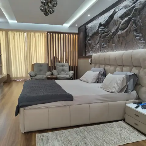 Master bedroom with a tufted beige leather bed set beneath a large sculptural mountain-relief wall panel, a sputnik-style chandelier