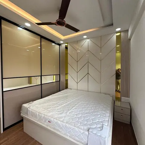 Master bedroom with a white gold-inlay chevron-pattern headboard wall, mirrored sliding wardrobe, and cove-lit ceiling with a ceiling fan