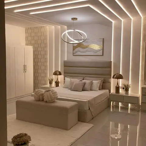Master bedroom with an elaborate multi-tier LED cove ceiling, a channel-tufted upholstered headboard, matching brass table lamps