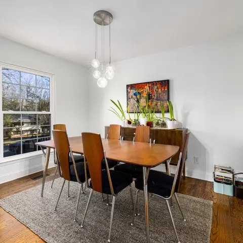Mid-century dining room with a wood table, black bentwood chairs on chrome legs and a cluster globe pendant light over a wood sideboard