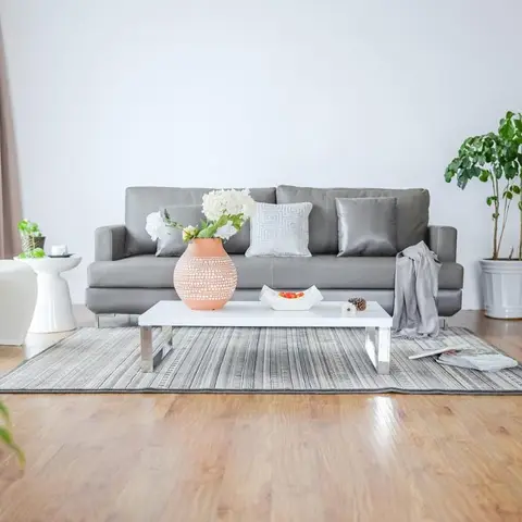 Minimal living room with a grey leather sofa, white gloss coffee table, a moulded white accent chair and a striped rug on wood flooring