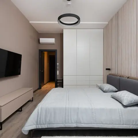 Minimalist bedroom with a two-tone tan and grey channel-tufted upholstered headboard, a wood-slat feature wall