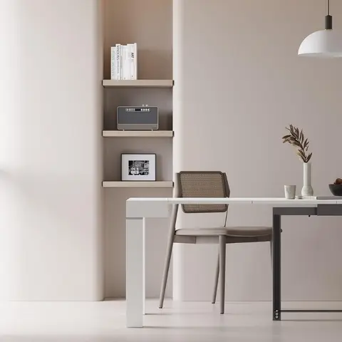 Minimalist dining nook with a white extendable table and cane-back chairs under a dome pendant light