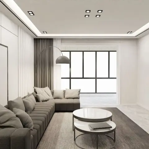 Minimalist living room with a channel-tufted grey L-shaped sofa, round nested marble coffee tables, an arc floor lamp