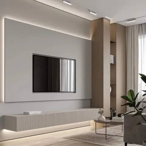 Minimalist living room with a wall-mounted TV on a backlit grey panel, a floating fluted-front console below, a wood-clad display column, sheer curtains