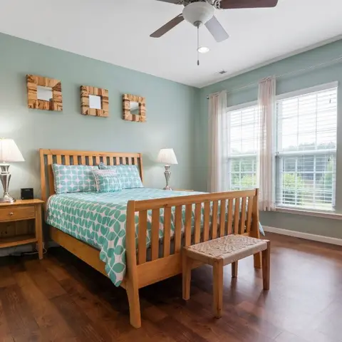 Mint-green bedroom with a light-oak slat sleigh bed under three small square rustic-framed mirrors, aqua geometric bedding