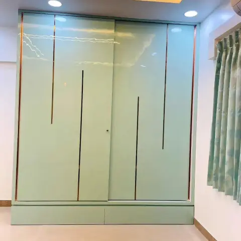 Mint-green high-gloss sliding wardrobe with rose-gold profile grooves and two base drawers, shot across a bed made up in panda-and-lion print bedding