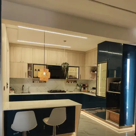 Modular kitchen in peacock-blue gloss and pale oak with an L-run under a marble-veined backsplash