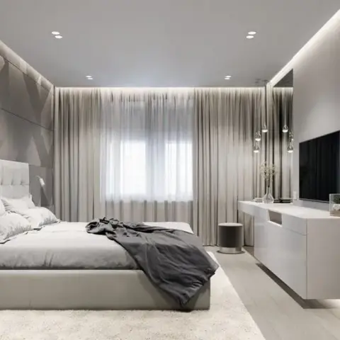 Monochrome grey master bedroom with a 3D geometric-panelled headboard wall and a floating TV console under cove lighting.