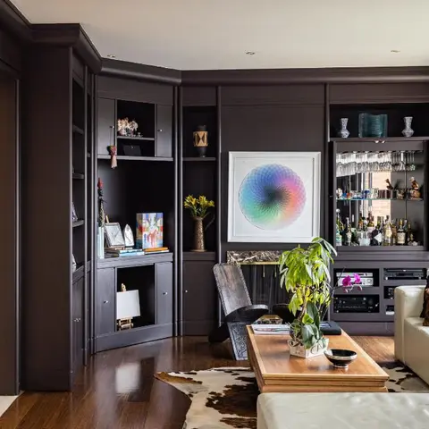 Moody charcoal living room with a floor-to-ceiling built-in wall unit housing a bar and display shelving