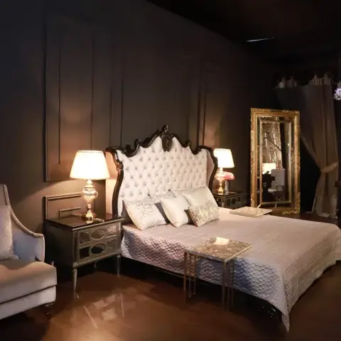 Moody dark bedroom vignette with a black tufted wingback headboard bed, a gilt floor mirror, a crystal chandelier
