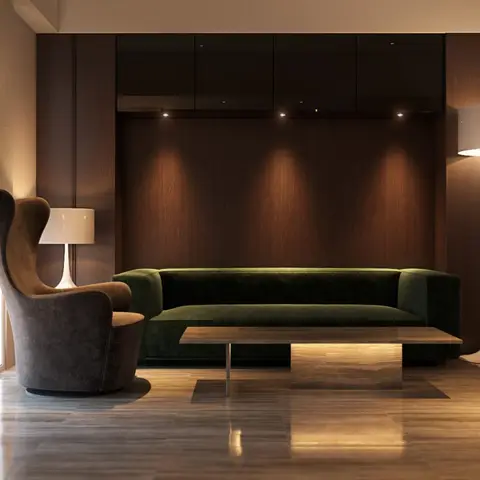 Moody living room with a dark green velvet sofa and swivel wingback chair against a spotlit wood panel wall, with a marble-and-wood coffee table