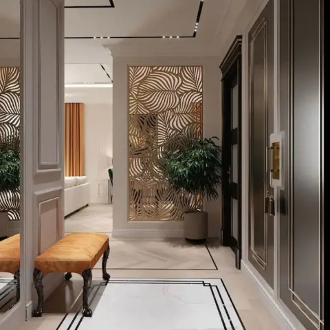 Moulded cream entry passage with a gold leaf-pattern jaali panel lit from behind, a mustard velvet bench on carved black legs
