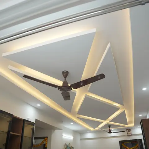 Multi-tier star-pattern POP false ceiling with continuous cove lighting and two ceiling fans