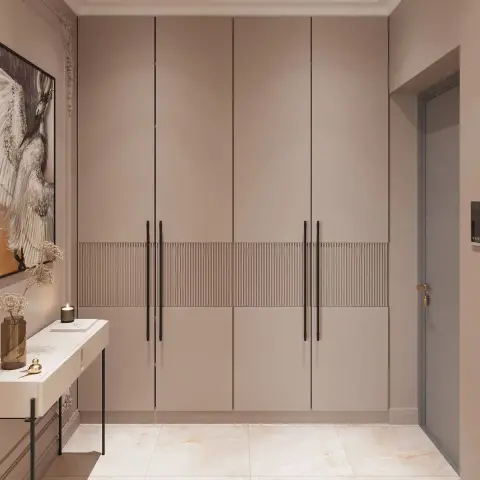 Mushroom-beige foyer where a full-height storage run with a fluted mid-band and long black bar handles faces a grey main door