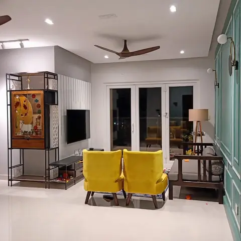 Mustard-yellow velvet armchairs facing a wall-mounted TV on a white fluted panel wall
