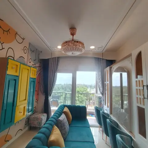 Narrow apartment living room with a long teal velvet channel-tufted sofa running the length of it