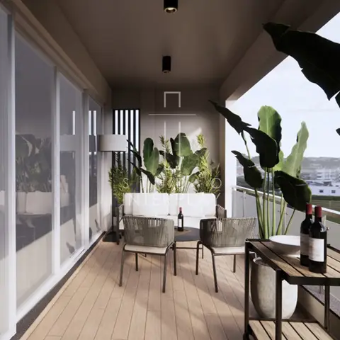 Narrow balcony fitted with a wood-look deck floor, a white sofa and woven outdoor armchairs around a round side table