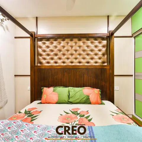 Narrow bedroom where a dark teak bed frame carries a buttoned bronze leatherette headboard over a fluted wood back