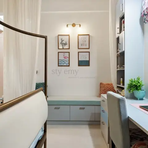 Narrow girl's room with a brass four-poster bed draped in white sheer at the left, blush-pink floor-to-ceiling wardrobes opposite