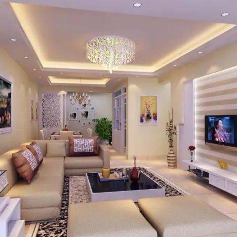 Narrow rectangular living room with a beige sectional and two matching ottomans on a black-and-cream damask rug, facing a horizontally striped backlit TV wall