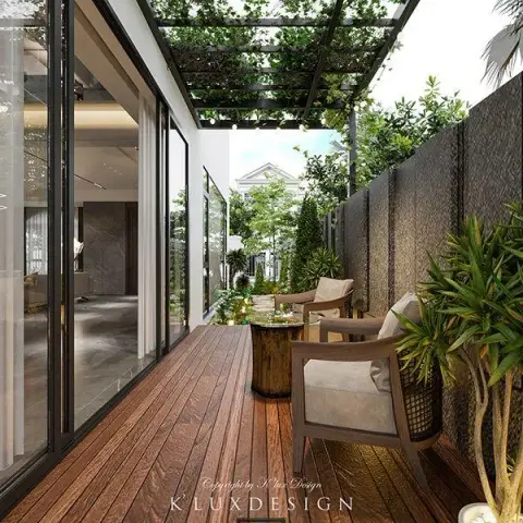 Narrow side deck running the length of a full-height sliding glass wall, with two teak-and-cane armchairs and a log-form side table on dark timber decking