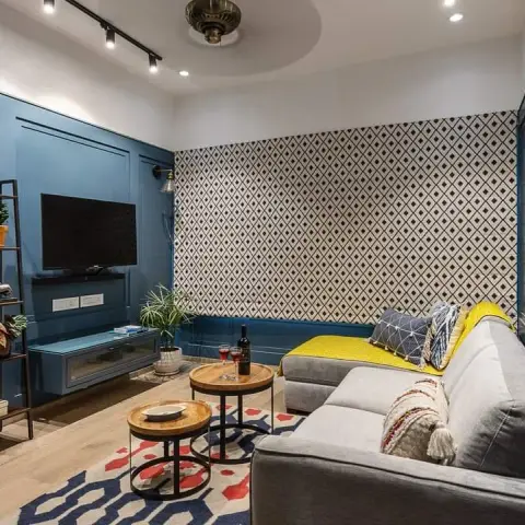 Narrow teal-panelled TV lounge with a black diamond-motif wallpaper end wall, a grey L-sofa with a mustard throw over the chaise