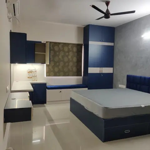 Navy laminate bedroom set — hydraulic storage bed with a channel-tufted blue velvet headboard against a grey textured wall, matching wardrobe