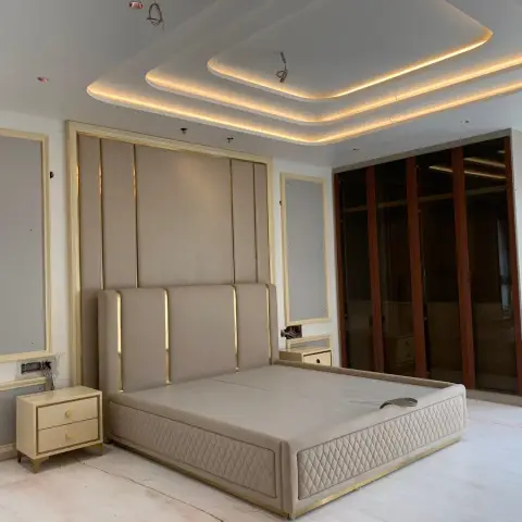 Near-finished bedroom with a tall channel-tufted headboard against gold-beaded upholstered wall panels