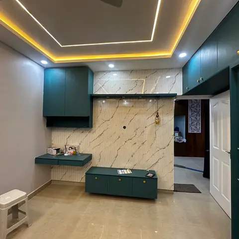 Newly finished living room with a teal fluted-panel TV console, marble-look fluted wall cladding, and a rectangular cove-lit false ceiling