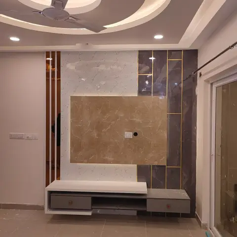 Newly finished, still-unfurnished TV wall in three marble-look tile tones — beige centre panel, white left field