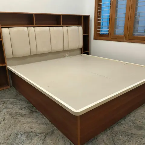 Newly fitted walnut-laminate storage bed with a channel-tufted cream headboard framed by open shelf niches