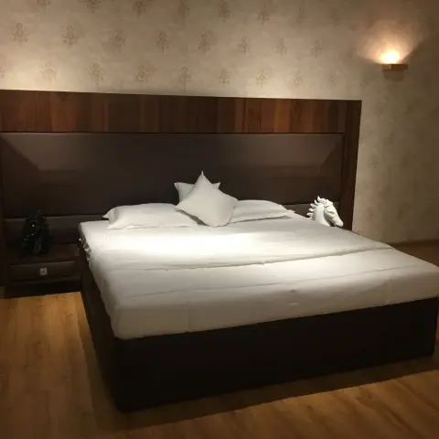 Newly handed-over bedroom with a full-width dark walnut headboard panel, cantilevered bedside shelves and a white horse-head bust