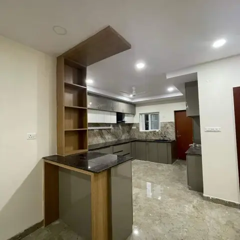 Newly handed-over L-shaped kitchen with grey gloss shutters and black granite, opening to a breakfast-bar peninsula whose oak-laminate frame carries a