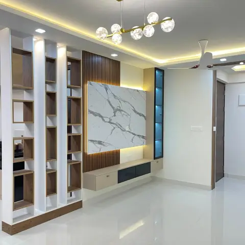 Newly handed-over living room, still unfurnished: a marble-look laminate TV back panel framed by walnut fluted strips, a slim backlit glass display column